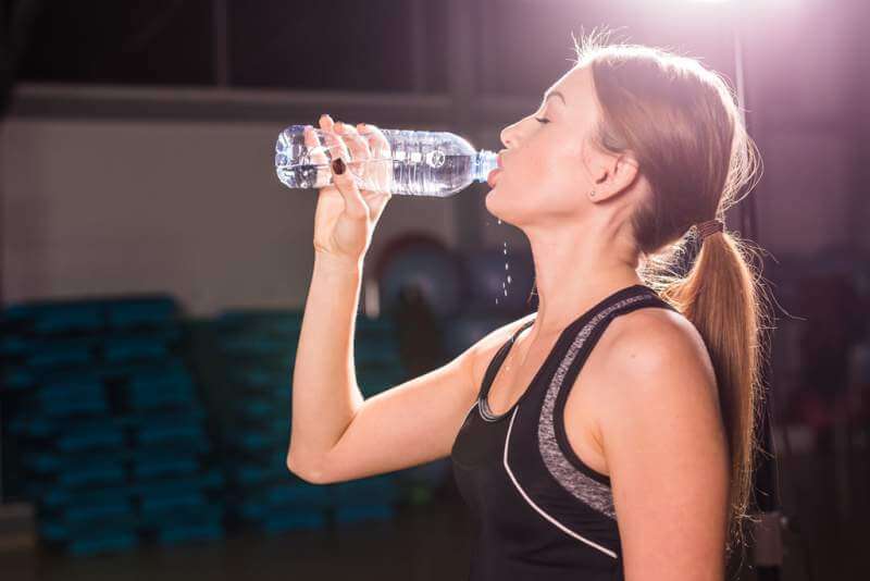 Beautiful fitness woman drinking water from the bottle