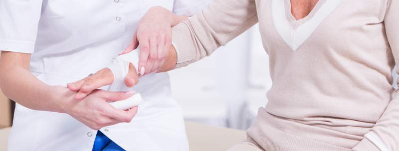 Doctor bandaging senior lady's hand