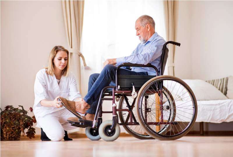 Nurse and senior man in wheelchair during home visit