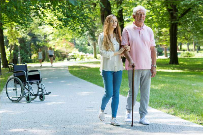 Woman helping elderly man with cane