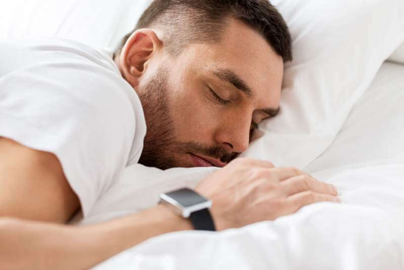 close-up-of-man-with-smartwatch-sleeping-in-bed