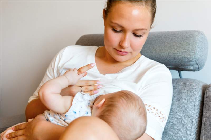 caring-young-mother-breastfeeds-baby-girl