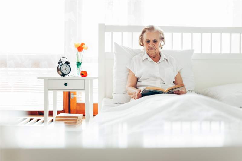 elderly-woman-sitting-comfortably-in-bed-reading