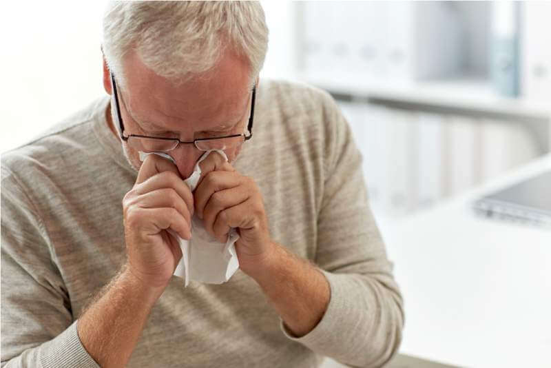 senior-man-blowing-nose-with-napkin-at-hospital