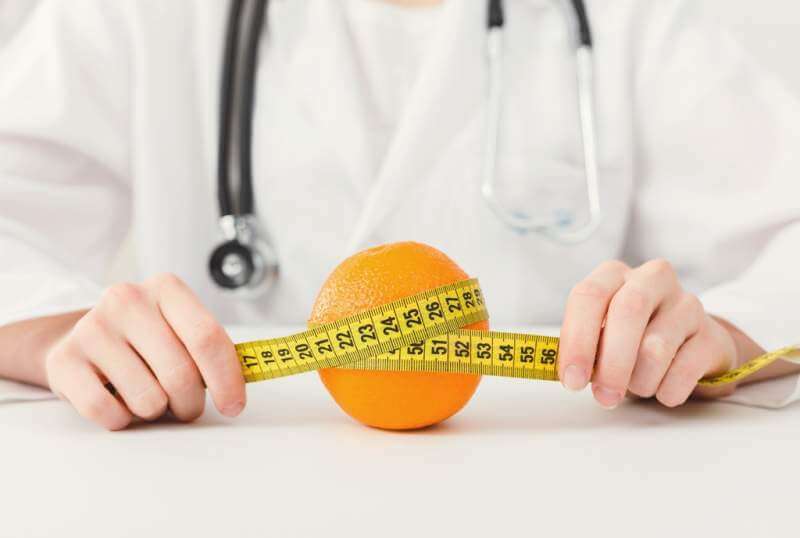 nutritionist-doctor-with-fruit-and-measuring-tape