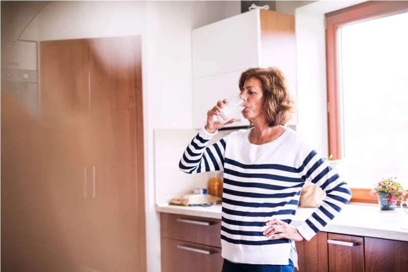 senior-woman-drinking-water-in-the-kitchen
