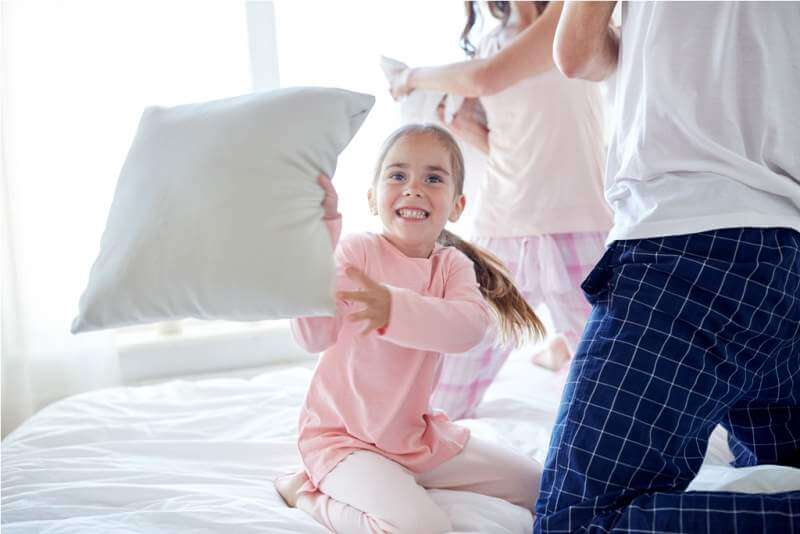 happy-family-having-pillow-fight-in-bed-at-home