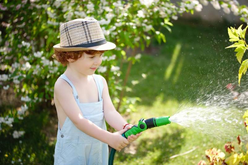 little-boy-watering-the-garden-with-hose
