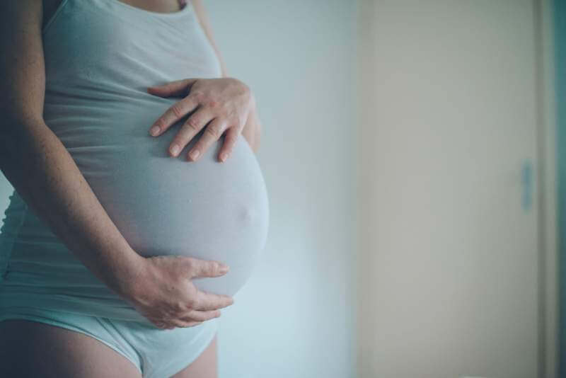 pregnant-woman-cuddling-belly-in-bedroom-at-home