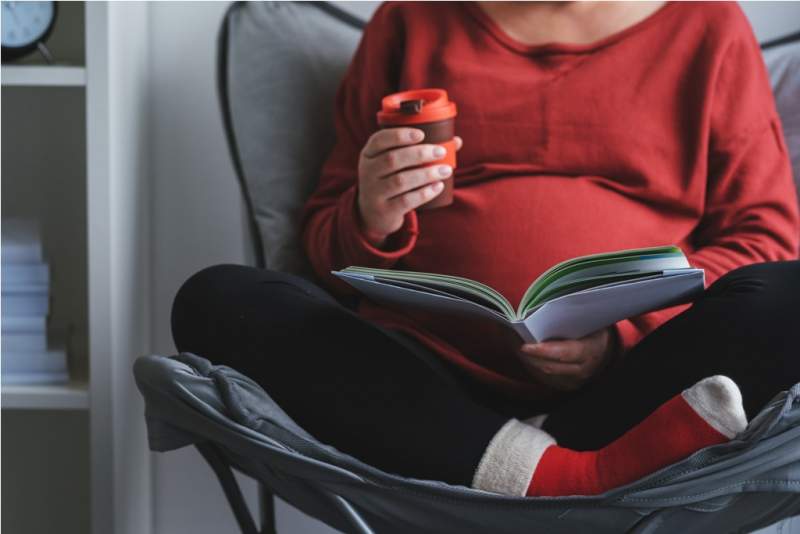 pregnant-woman-reading-book-in-living-room