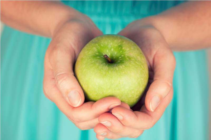 womans-hands-holding-a-green-apple