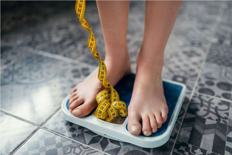 female-feet-on-the-scales-closeup-measuring-tape