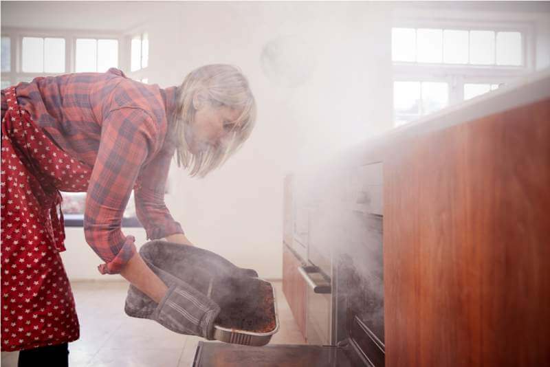 middle-aged-woman-opening-smoke-filled-oven
