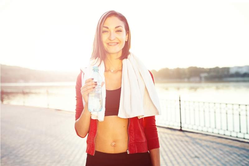 woman-holding-bottle-of-water-and-a-towel