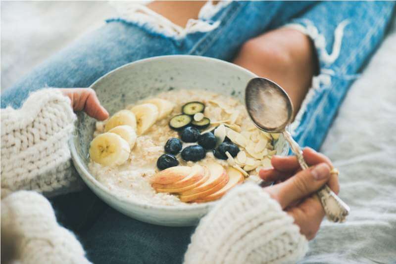 woman-in-jeans-and-sweater-eating-healthy-oatmeal