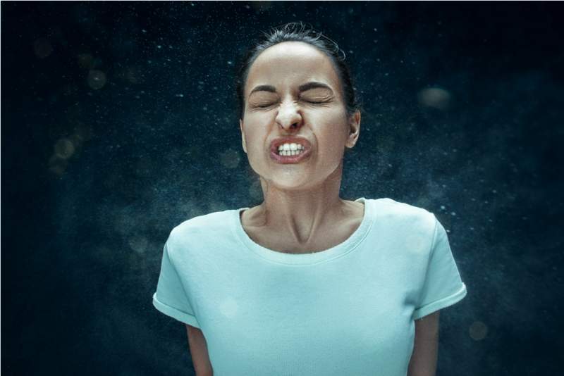 young-woman-sneezing-studio-portrait