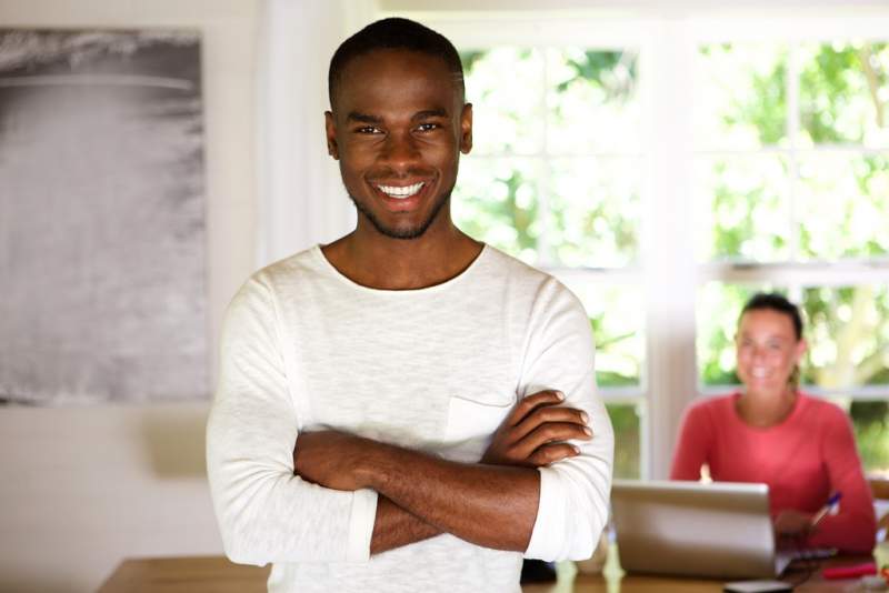 happy-young-african-man-standing-with-his-arms