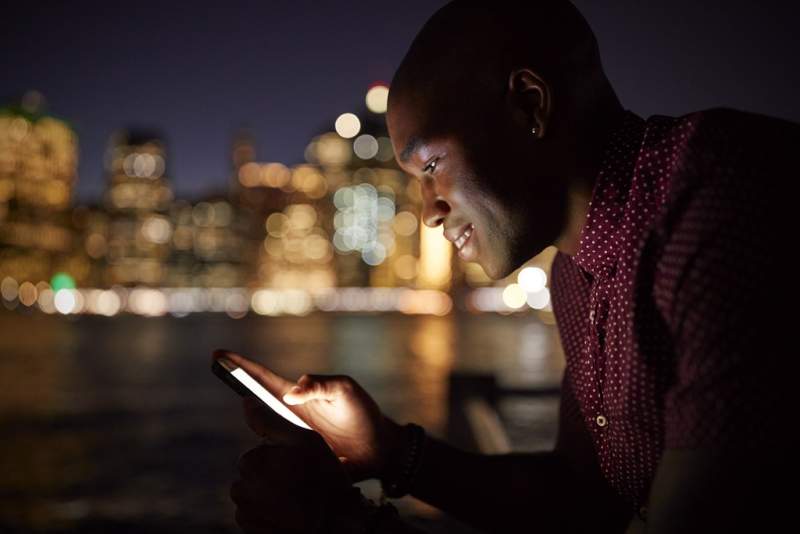 man-using-mobile-phone-at-night-with-city-skyline
