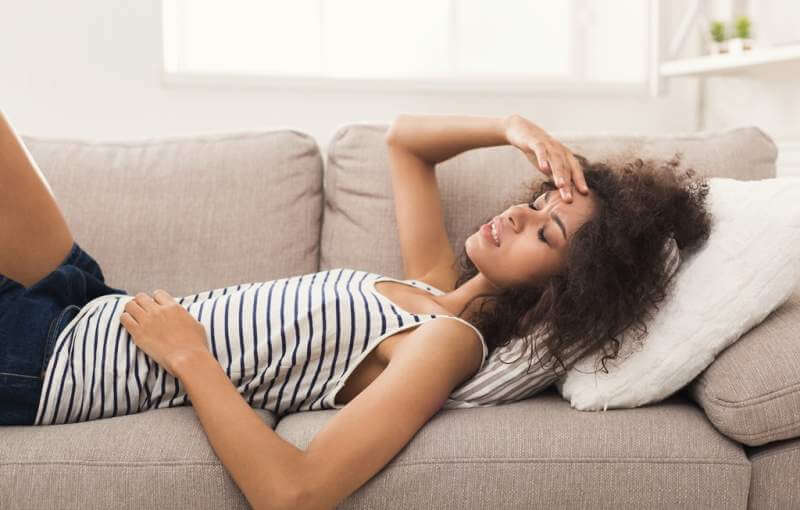 sad-black-girl-feeling-pain-lying-on-sofa