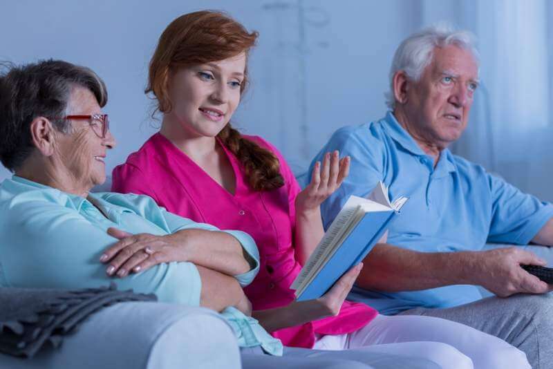 caregiver-reading-to-elderly-woman