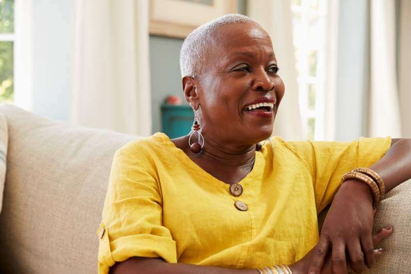 smiling-senior-woman-sitting-on-sofa-at-home