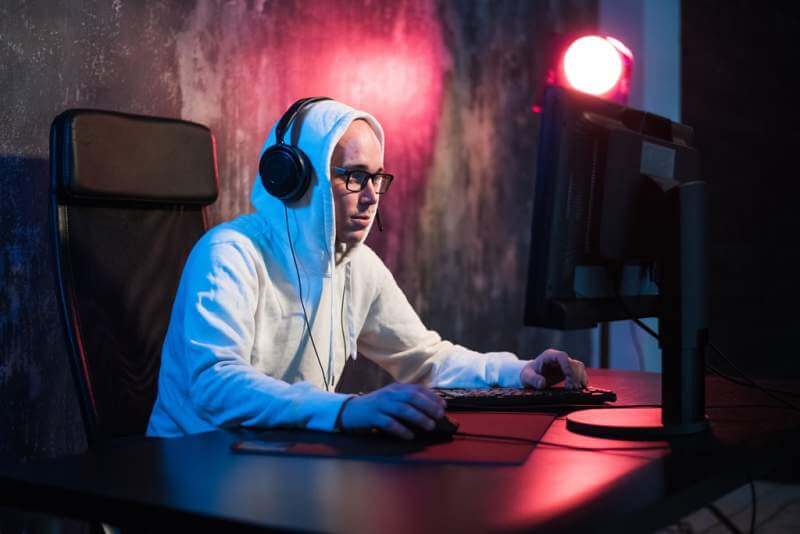 male-hooded-gamer-playing-online-game-on-pc