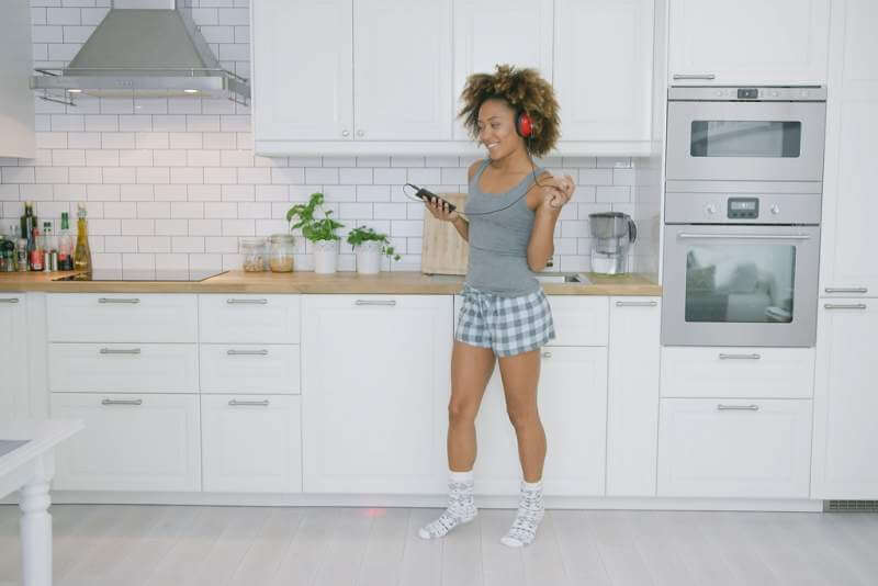 young-woman-dancing-in-kitchen-with-smartphone