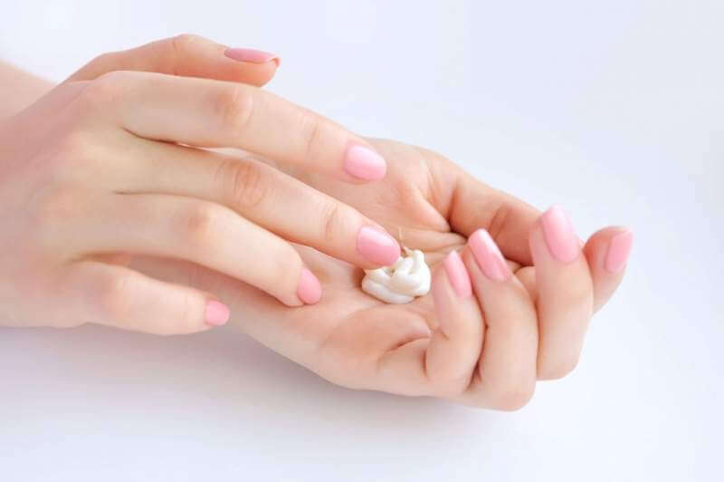 young-woman-with-pink-manicure-applies-cream