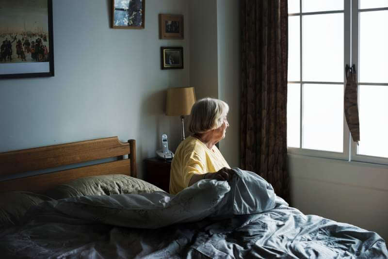 senior-woman-sitting-in-a-bedroomjpg