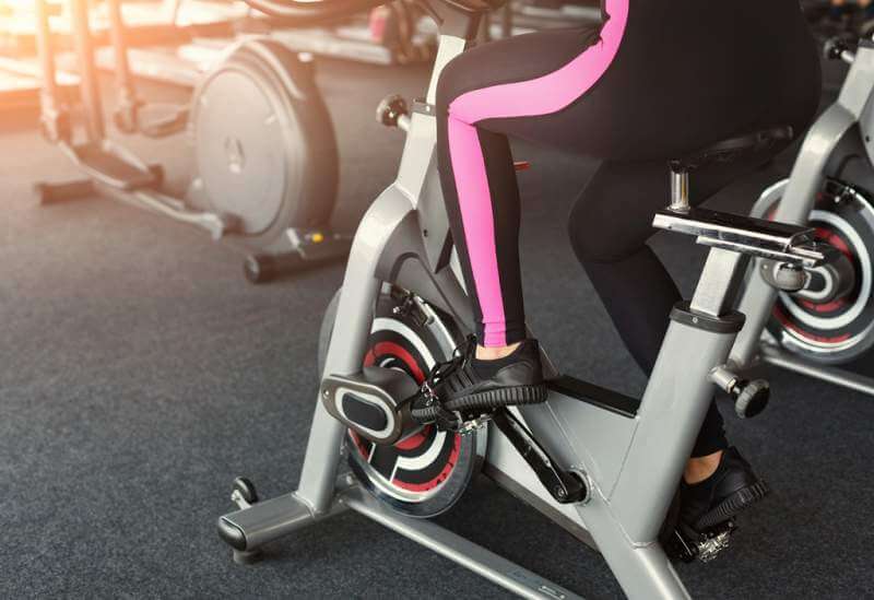 womans-legs-on-exercise-bikes-in-fitness-club