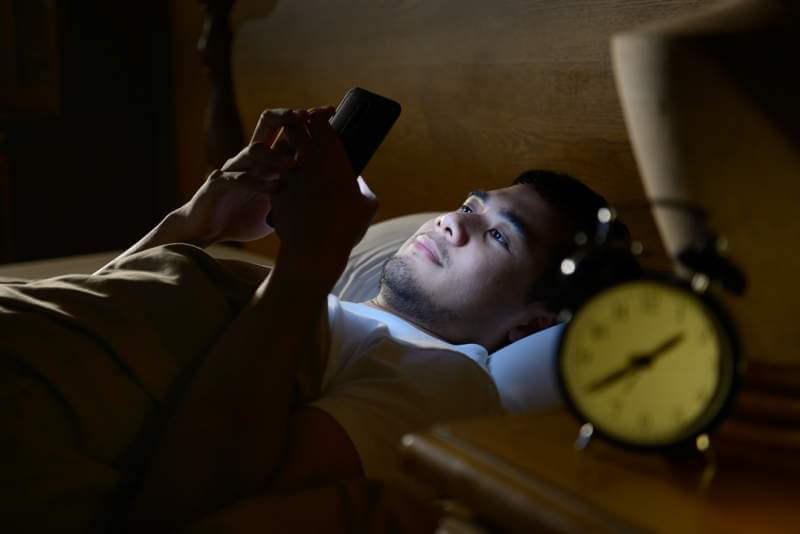 young-man-using-a-smartphone-in-his-bed-at-night