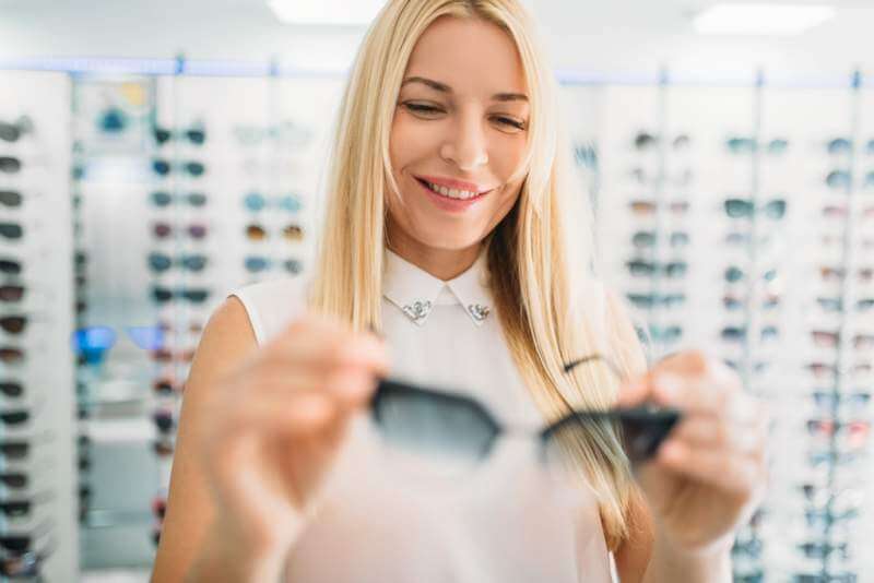 female-optician-shows-sunglasses-in-optics-store