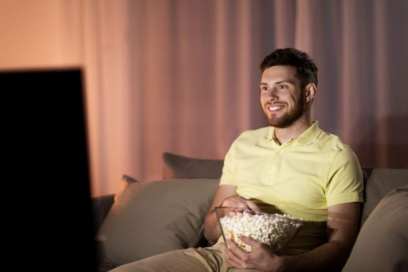happy-man-with-popcorn-watching-tv-at-night