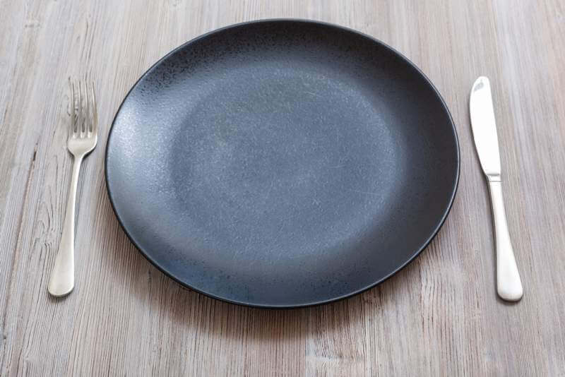 black-plate-with-knife-spoon-on-gray-brown-table