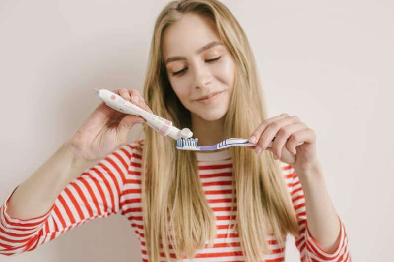cute-young-girl-with-tooth-brush-is-pressing-a-toothpaste-on-it