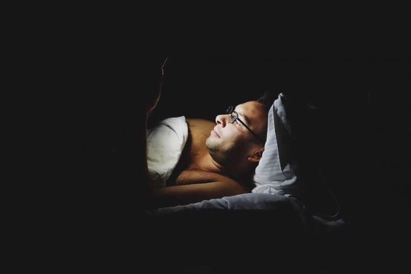 man-using-mobile-device-in-bed-before-sleep