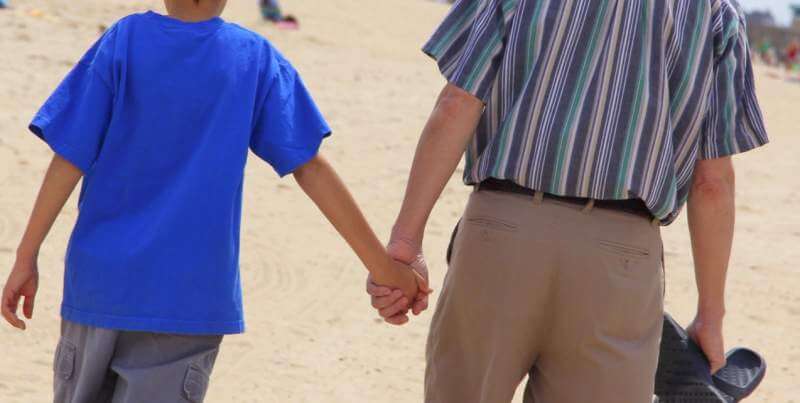 teen-holding-his-dad-s-hand-while-talking-walking