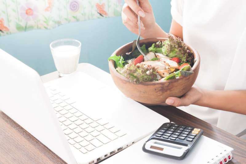 Woman eating chicken salad during working